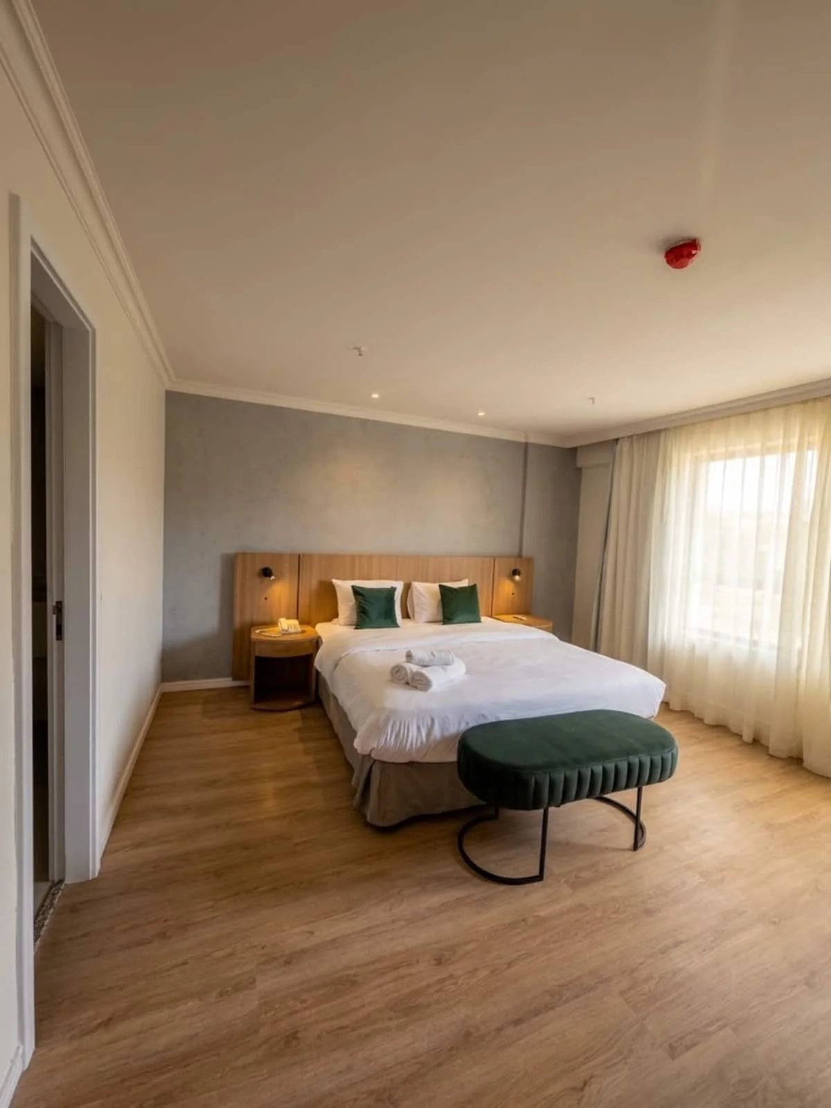 Quarto com cama de casal, puff verde e janela ampla