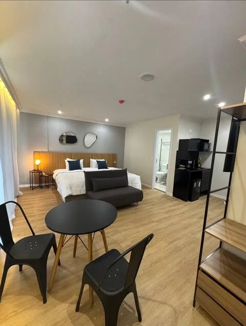 Studio com cama de casal, sofá-cama e mesa com cadeiras