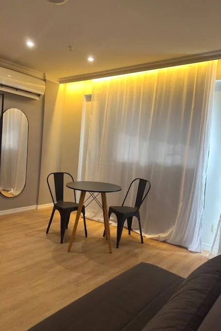 Mesa com duas cadeiras e cortina com iluminação indireta