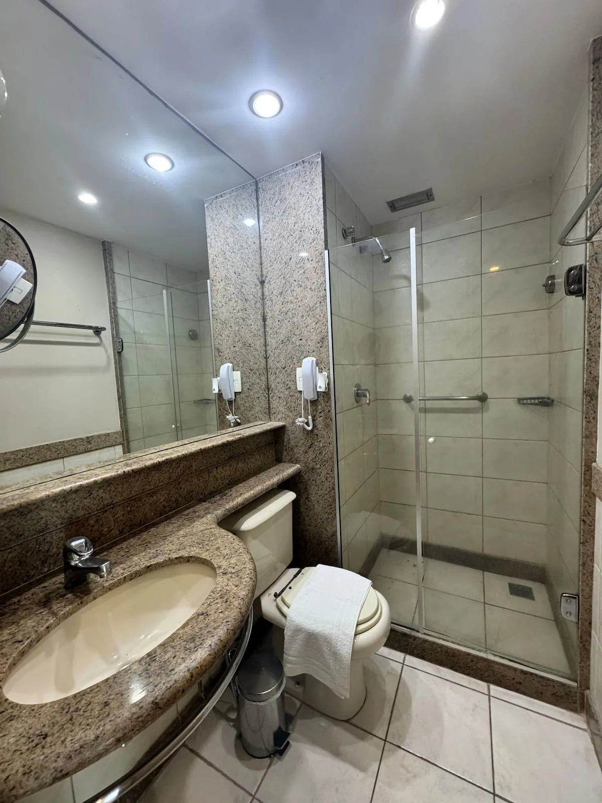 Banheiro com bancada de granito e box de vidro