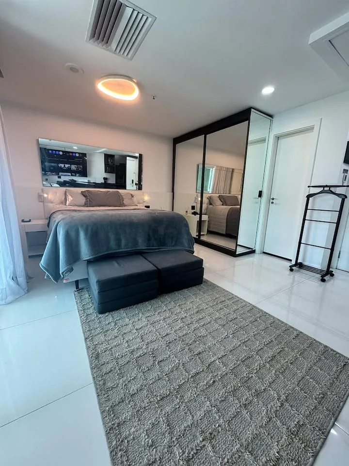 Quarto com cama queen, baú puff e armário espelhado